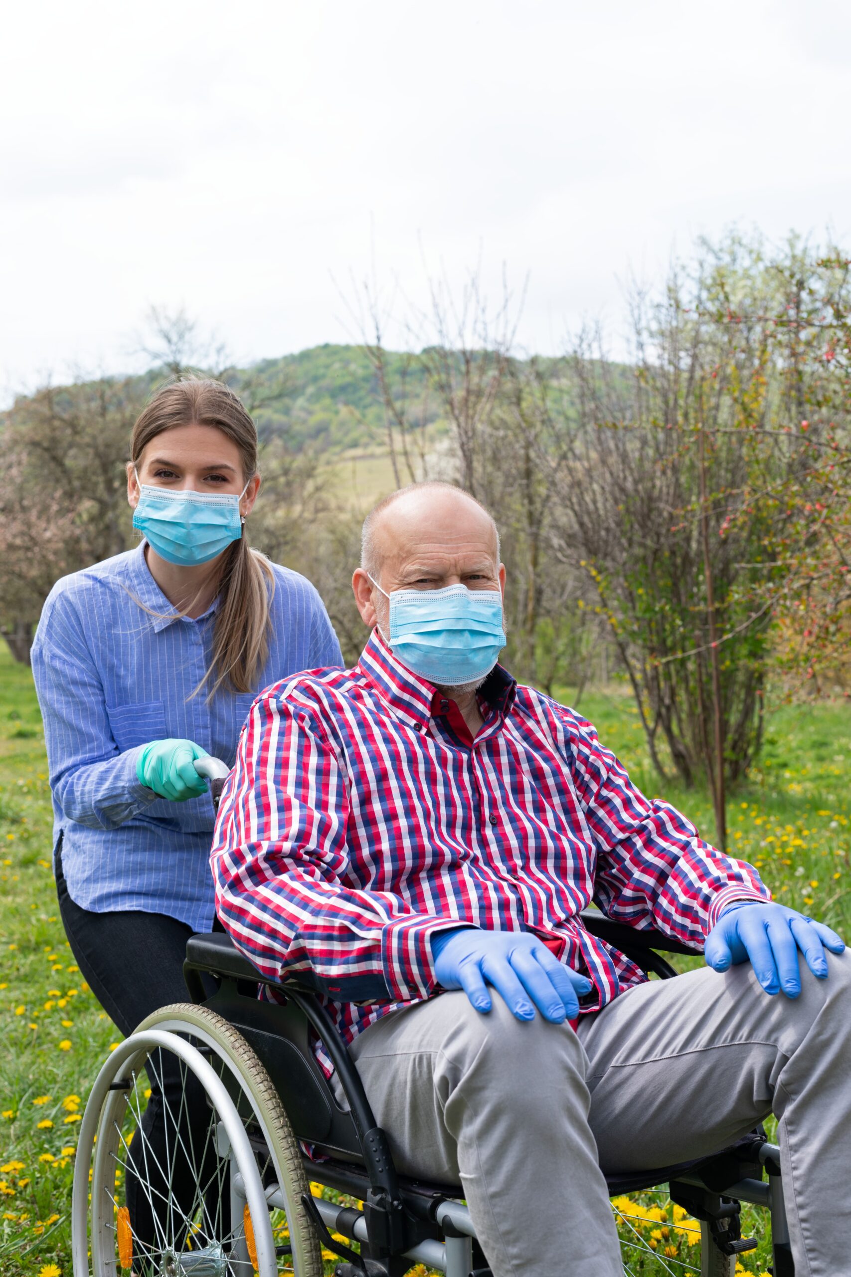 A caretaker and the senior go out in masks and gloves