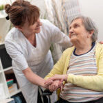 A nurse is caressing the old woman in the wheel chair