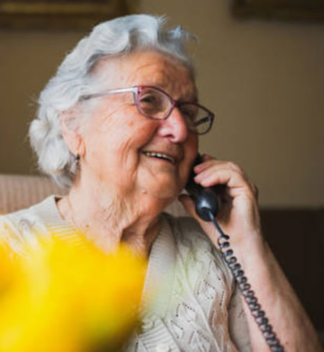 An old woman smiling and speaking on the telephone