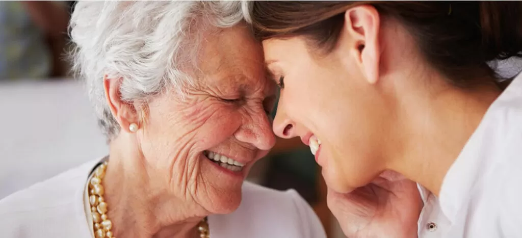 A woman and an old lady smiling at each other.