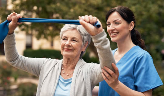 A caretaker helping the old woman in doing exercises