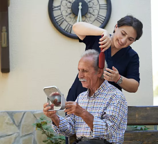 A woman is combing the hair of an older man.