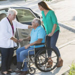 A woman taking the man in wheel chair to the car