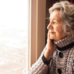 A senior woman sitting and looking out from the window