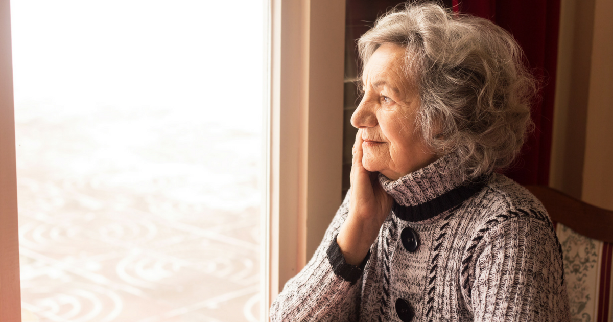 A senior woman sitting and looking out from the window