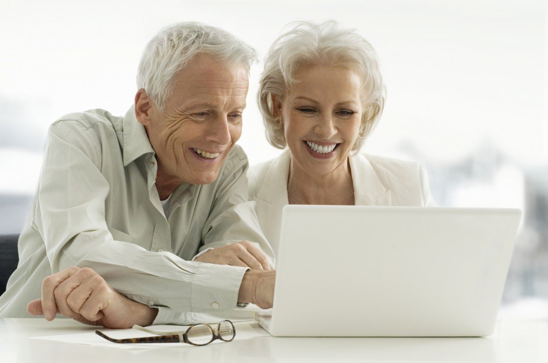 An old couple sitting together and watching laptop