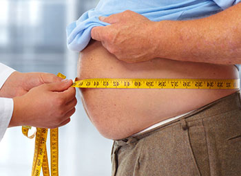 A doctor is measuring the obese belly of the man