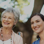A caregiver and senior female patient smiling and posing