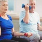 A senior couple sitting and doing a workout with dumbbells