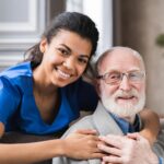A nurse holding the old man's shoulder and posing