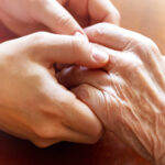 caregiver and senior client holding hands - In Home Dementia Care Carmel CA