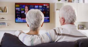An old couple sitting and watching the television